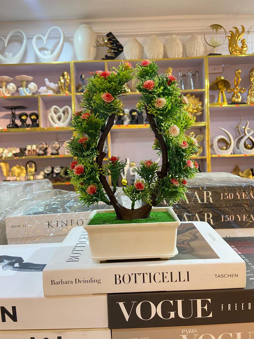Bonsai tree with pink flowers on decorative books