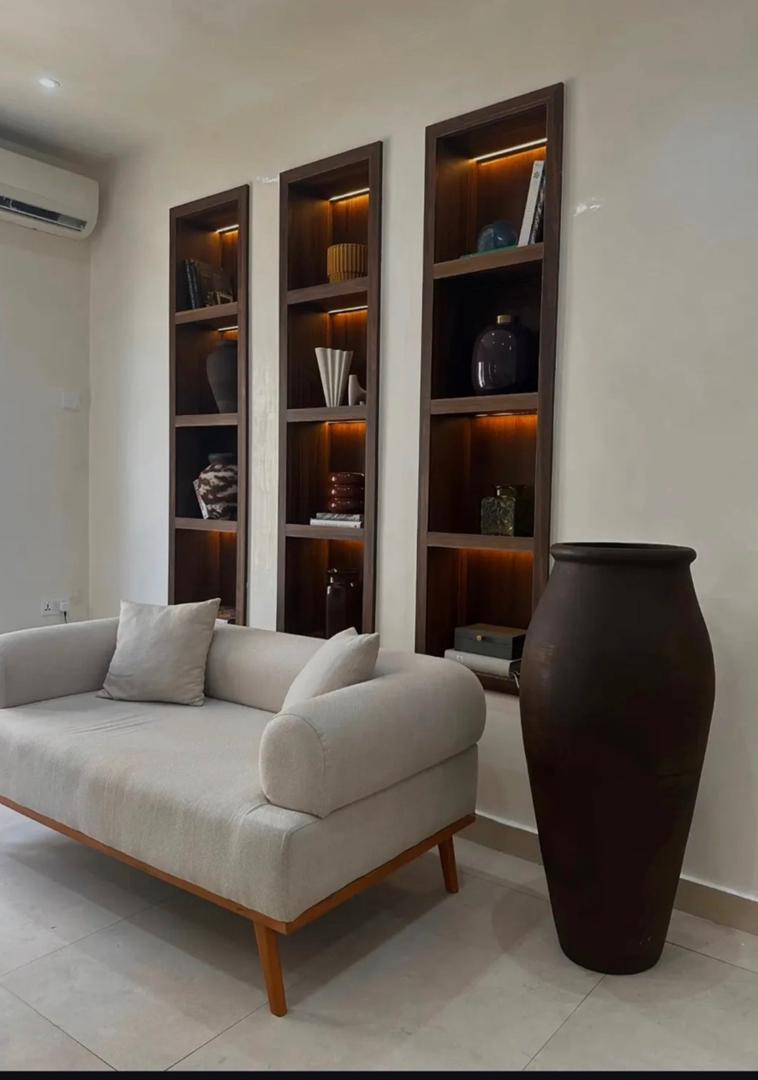 Styled living room with illuminated shelving and floor vase
