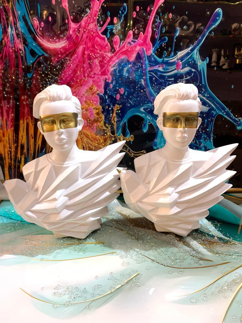 White geometric busts with gold face masks